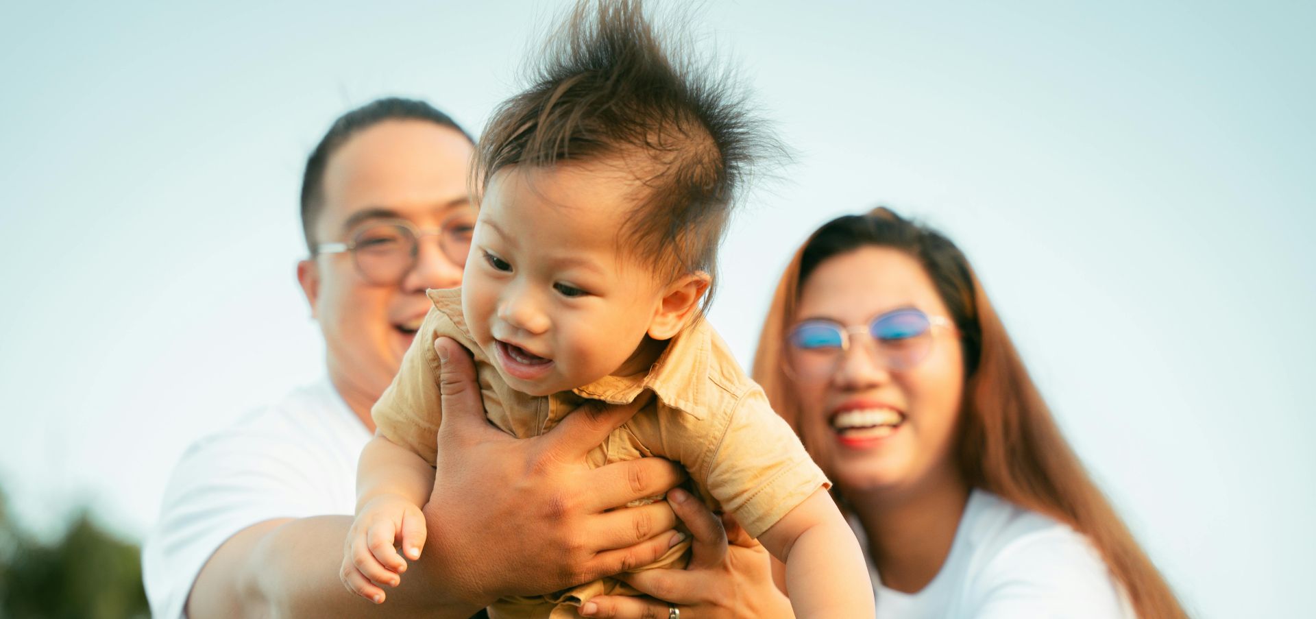 A family is holding a baby in the air